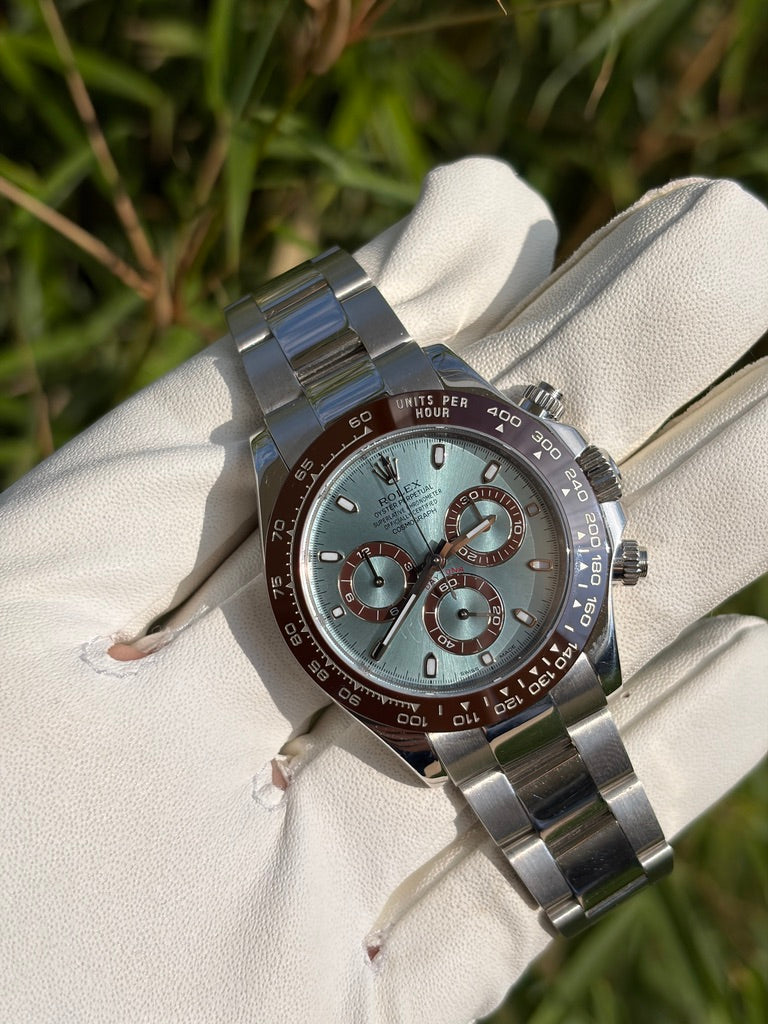 Rolex Cosmograph Daytona 40 mm, Referenz 116506, aus Platin mit eisblauem Zifferblatt, braunen Totalisatoren, kastanienbrauner Cerachrom-Lünette und Oyster-Armband, auf einem weißen Handschuh präsentiert.