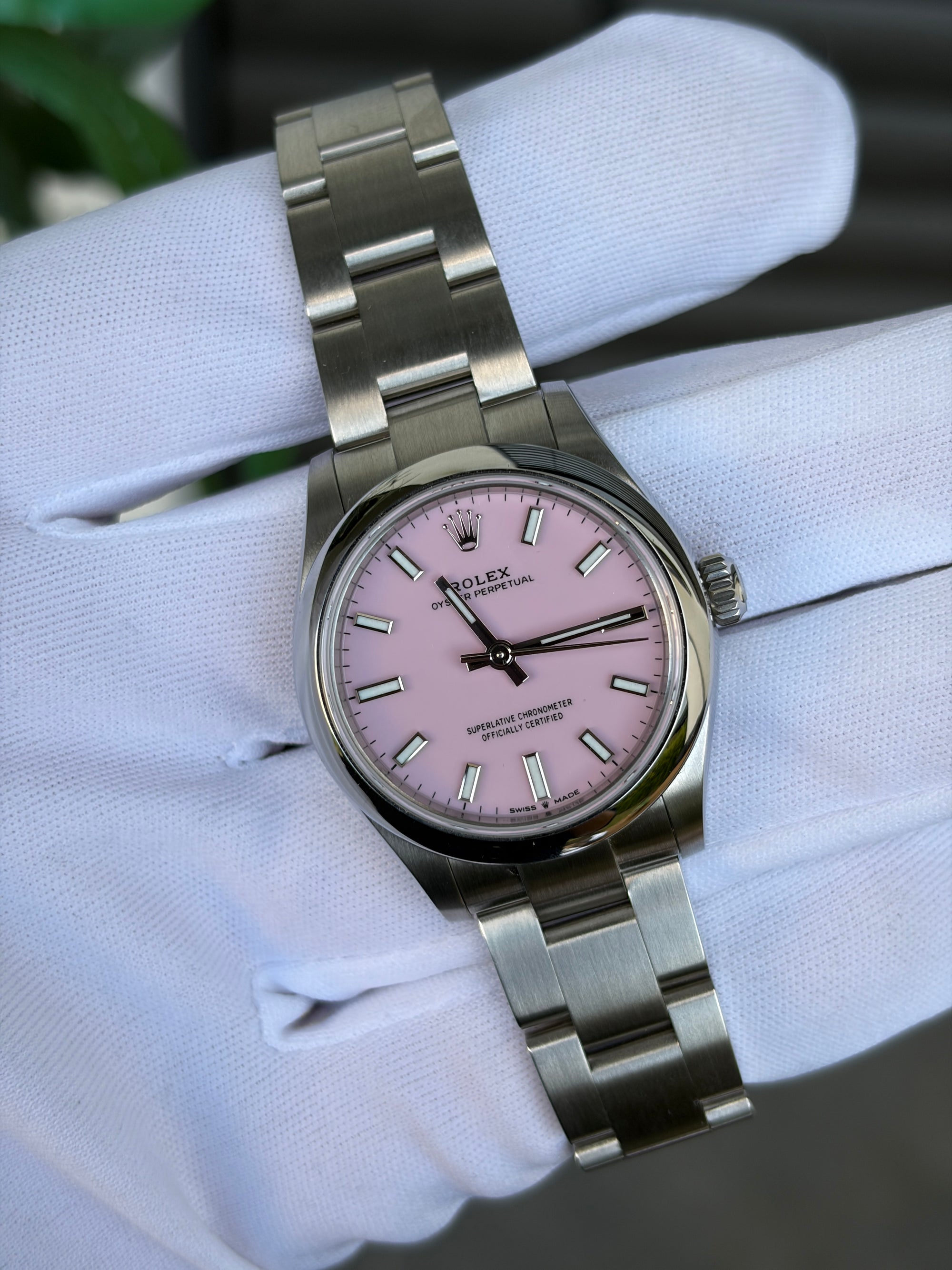 Rolex Oyster Perpetual 31 mm, Referenz 277200, aus Edelstahl mit Candy-Pink-Zifferblatt und Oyster-Armband, gehalten mit weißem Handschuh.