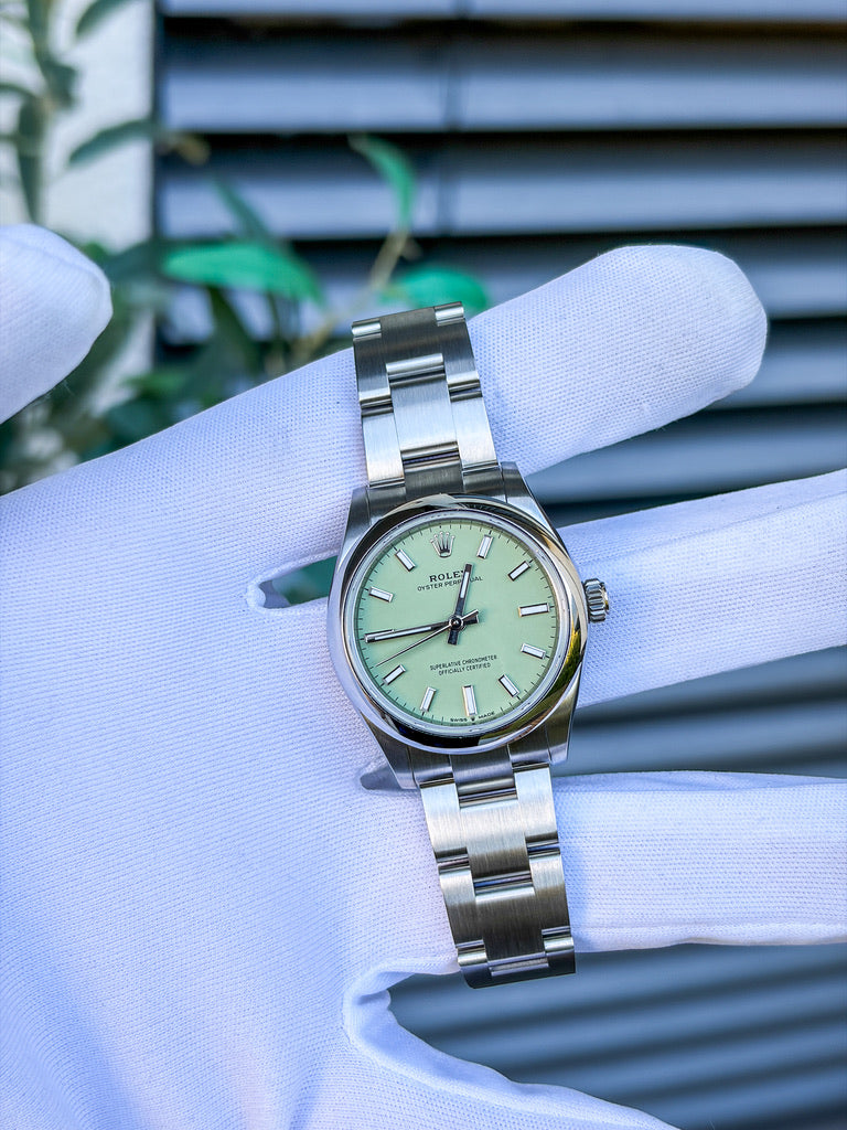 Rolex Oyster Perpetual 31 mm, Referenz 277200, aus Edelstahl mit pistaziengrünem Zifferblatt, glatter Lünette und Oyster-Armband, auf einem weißen Handschuh präsentiert.